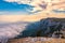 Majestic orange sunset over the rocky mountains and the valley in fog and clouds. Creamy fog covered the mountain valley in sunset