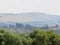 A majestic photo of a farmland landscape over a green bushy treetop