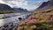 Majestic River In Iceland With Purple Flowers And Mountain Views