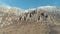 Majestic rock formation on a green mountainside covered by shrubs on a clear sunny day against the blue clear sky. Shot