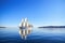 majestic sailboat gliding through calm waters, with clear blue skies and greenery in the background