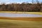 A majestic shot of a golf course with autumn colored grass surrounded by green and autumn colored trees