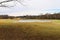 A majestic shot of a golf course with autumn colored grass surrounded by green and autumn colored trees