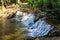 A majestic shot of a waterfall on South Fork Peachtree Creek surrounded by lush green trees reflecting off the water at Lullwater