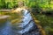 A majestic shot of a waterfall on South Fork Peachtree Creek surrounded by lush green trees reflecting off the water at Lullwater