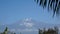 Majestic snowcapped Mount Kilimanjaro in Tanzania framed by palm fronds and trees