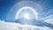 Majestic solar halo and full circle rainbow surrounding the sun above the snowy mountain peak create a breathtaking