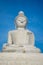 Majestic statue of Buddha sitting on a set of stairs against a bright blue sky.