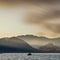 Majestic sunrise landscape looking across Derwent Water in Lake District with misty sun beams lighting the mountains