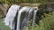 Majestic tiered waterfall flows gracefully surrounded by early fall foliage