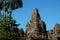 The majestic towers of Bayon Temple, in Cambodia. Tall tropical trees. Beautiful landscape