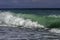 Majestic Turquoise and bright green swell crashing into a beach on a blue sky summer day in Sicily