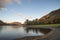 Majestic vibrant Autumn Fall landscape Buttermere in Lake District with beautiful early morning sunlight playing across the hills