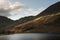 Majestic vibrant Autumn Fall landscape Buttermere in Lake District with beautiful early morning sunlight playing across the hills