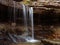 Majestic waterfall cascading down a rocky outcrop surrounded by vibrant foliage in autumnal hues