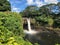 Majestic waterfall cascading over a large expanse of tranquil water with a rainbow above. Hawaii.