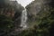 majestic waterfall crashing over rugged rock formation, with mist rising from the cascade