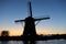 Majestic windmill illuminated in the sky as the sun sets over a tranquil body of water