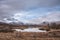 Majestic Winter panorama landscape image of mountain range and peaks viewed from Loch Ba in Scottish Highlands with dramatic