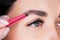 We make eyebrows with pink tweezers, close-up background for the eyebrow