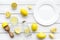 Make lemonade at home. Lemons, juicer, glass and bottle for beverage on white wooden background top view mockup