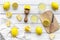 Make lemonade at home. Lemons, juicer, glass, knife, cutting board on white wooden background top view