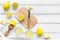 Make lemonade at home. Lemons, juicer, glass, knife, cutting board on white wooden background top view copyspace