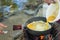 Make an omelette on the pan in hot oil, place on the stove, prepare breakfast for hiking or camping using as travel concept.