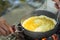Make an omelette on the pan in hot oil, place on the stove, prepare breakfast for hiking or camping using as travel concept.