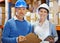 We make a smart team. Portrait of two employees wearing hardhats standing with clipboards in a warehouse.