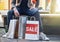 Make sure you never miss a sale. a man sitting on a bench with his shopping bags on the floor.