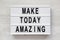 `Make today amazing` words on a modern board on a white wooden background. From above, overhead, flat lay, top view. Closeup