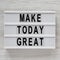 `Make today great` words on a modern board over white wooden surface, top view. Overhead, from above. Flat lay