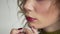 Make-up artist apply lipstick with brush. Close-up of female model face with fashion glossy red lips makeup, beauty
