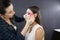 A make-up artist is applying makeup to a young girl.