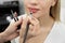 Make-up artist cosmetologist paints her lips before a permanent makeup procedure