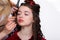 Make-up artist and hairdresser prepares beautiful young woman in the beauty salon makes a hair curling and makeup