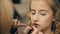 Make-up artist makes young actress girl beautiful makeup for lips before dancing perfomance indoors