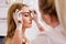 Make up and beauty concept - young beautiful blonde woman gettting eyebrow painting procedure