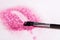 Make up brush making stroke on pink glitters