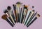 Make up the essentials. A set of professional makeup brushes on pink background