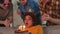 Make a wish. Woman wearing party cap blowing out burning candles on birthday cake. Happy Birthday party. Group of