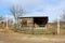 Makeshift homemade dilapidated wooden frame and wire fence entrance doors preventing access to small old wooden storage shed