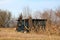 Makeshift homemade small wooden shed covered with protective nylon sheets surrounded with dry cornfield and trees