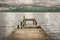 A makeshift stone jetty in a lake, mountains and storm clouds.