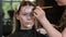 Makeup artist applies cosmetics to face of young woman in beauty salon