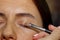 Makeup artist applies eye shadow . Beautiful woman face. Hand of visagiste, painting cosmetics of young beauty model girl . Make
