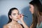 Makeup artist applies eye shadow. Hand of visagiste, painting cosmetics of young beauty model girl. Fashion shiny