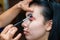 Makeup artist applying eyeshadow on a beautiful girl. Make up artist doing professional make up of beautiful young woman.