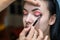 Makeup artist applying eyeshadow on a beautiful girl. Make up artist doing professional make up of beautiful young woman.